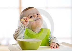 Happy baby boy spoon eats itself