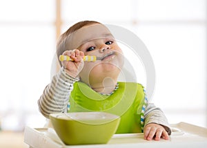 Happy baby boy spoon eats itself photo