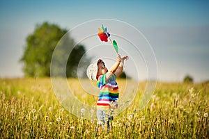 Baby boy standing in grass on the fieald with dandelions