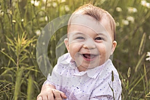 Happy baby boy standing in grass on the field of daisy