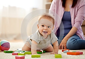 Happy baby boy with toy blocks on carpet at home