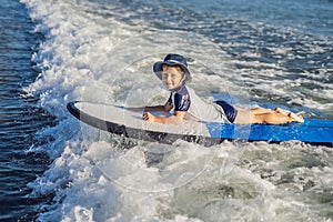 Happy baby boy - young surfer ride on surfboard with fun on sea