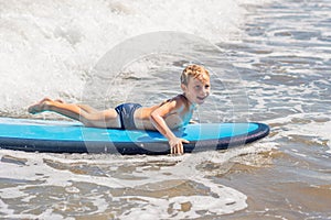 Happy baby boy - young surfer ride on surfboard with fun on sea