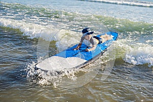 Happy baby boy - young surfer ride on surfboard with fun on sea waves. Active family lifestyle, kids outdoor water sport