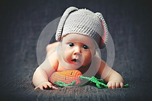 Happy baby child in costume a rabbit bunny with carrot on a grey