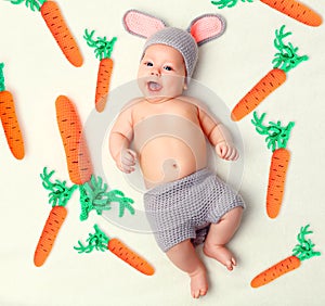 Happy baby child in costume a rabbit bunny with carrot on a whit