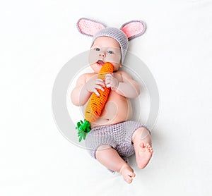 Happy baby child in costume a rabbit bunny with carrot on a whit