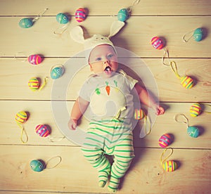 Happy baby child with Easter bunny ears and eggs