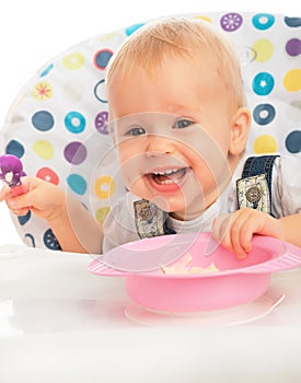 Happy baby child eats itself with a spoon