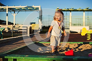 Happy baby child playing with the sand at the playground