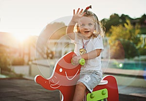 Happy baby child riding a red elephant at the playground