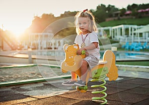 Happy baby child riding a yellow cow at the playground