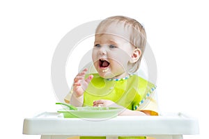 Happy baby child sitting in chair with a spoon