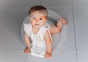 Happy baby crawling on the tiled floor
