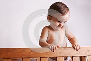 Happy baby in crib, playing with smile and fun in home, child development and care in house. Toddler girl in cot with