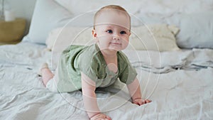 Happy baby. Cute little newborn girl with smiling face crawling on bed in bedroom. Infant baby resting playing lying