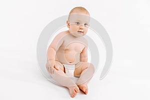 Happy baby in diaper sitting on isolated white background
