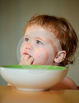 Happy baby eating himself with a spoon. Lick tasty fingers.