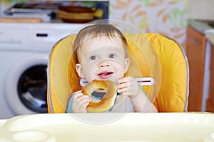 Happy baby eating round cracknel on kitchen photo