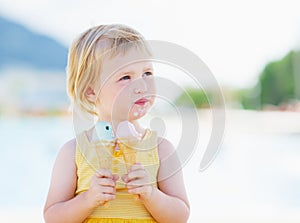 Happy baby eating two ice cream horns and looking on copy space