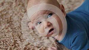 Happy baby face close up emotions, newborn child on bed smiling