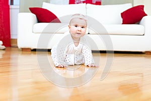 Happy baby girl crawling on a hardwood floor