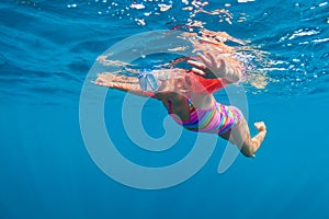 Happy baby girl dive underwater in sea pool