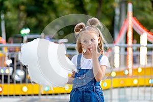 Happy baby girl eating cotton candy at amusement Park in summer