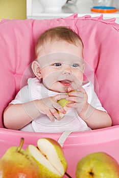 Happy baby girl eating fruit