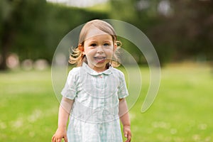 Happy baby girl on green summer field