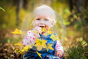 Happy baby girl laughing and playing in the autumn on the forest