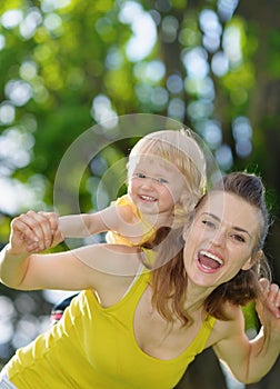 Happy baby girl piggybacking mother