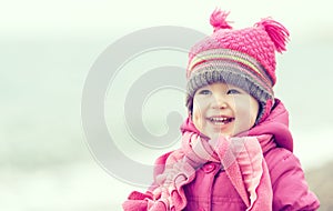 Happy baby girl in a pink hat and scarf