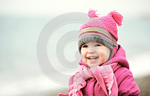 Happy baby girl in pink hat and scarf laughs