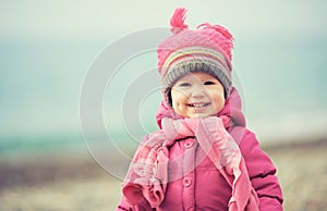 Happy baby girl in pink hat and scarf laughs