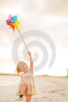 Happy baby girl playing with colorful windmill toy