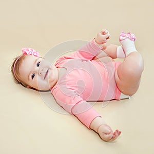 Happy baby girl playing with her feet