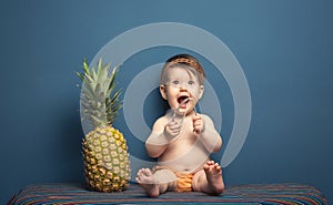 Happy baby girl playing with a pineapple