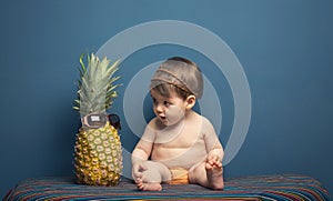 Happy baby girl playing with a pineapple