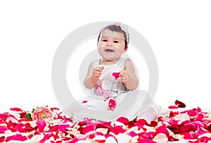 Happy baby girl among rose petals