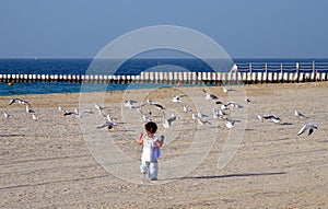 A happy baby girl running at the beach with white sand in Dubai, UAE