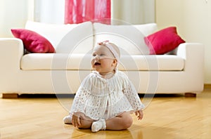 Happy baby girl seated on a hardwood floor
