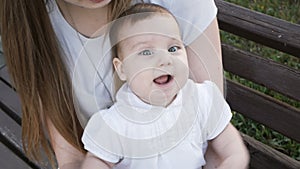 Happy baby girl sitting on the bench in park