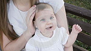 Happy baby girl sitting on the bench in park