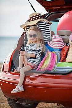 Happy baby girl sitting in the car trunk