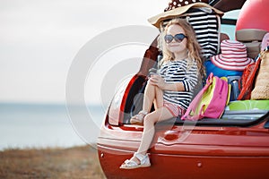 Happy baby girl sitting in the car trunk