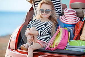 Happy baby girl sitting in the car trunk