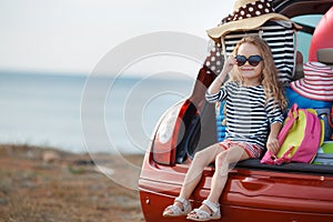 Happy baby girl sitting in the car trunk