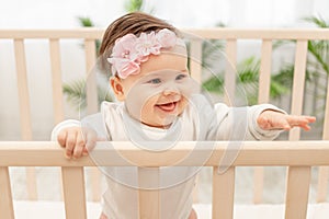 Happy baby girl six months standing in the crib