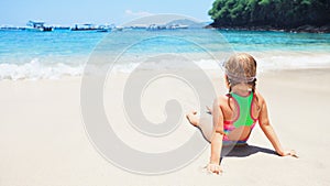 Happy baby girl in snorkeling mask sit on sand beach